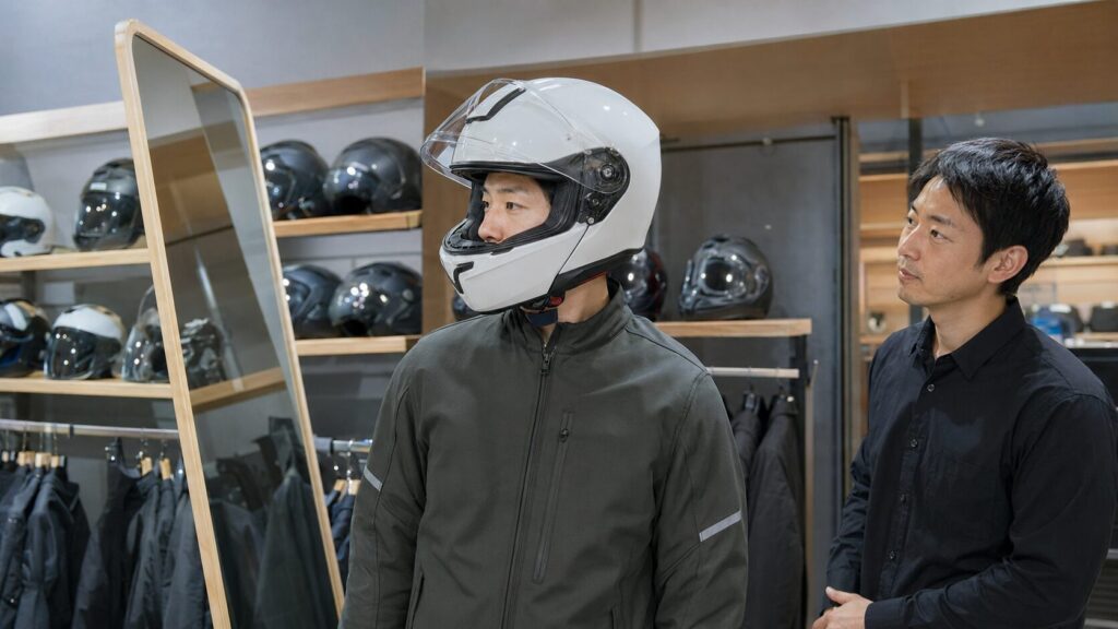 店頭で軽量バイクヘルメットの重心とフィット感を確認する日本人ライダー