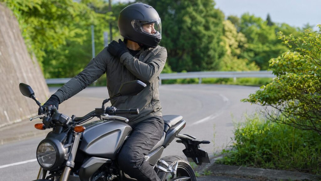 中型ネイキッドバイクで後方確認する日本人ライダーとフルフェイスヘルメット