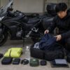 ツーリングに必要な装備と工具をバッグへ整理するライダー