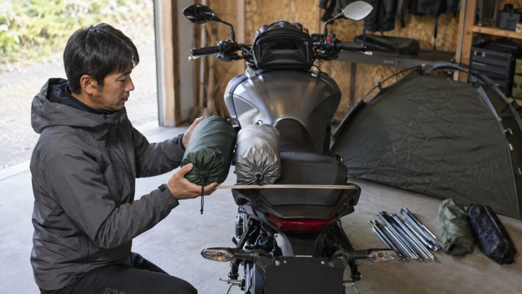収納したテントがバイクの車幅に収まるか確認するライダー