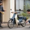 原付スクーターのそばで鍵と必要書類を準備する日本人オーナー