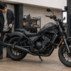 黒い認証対応マフラーを装着したレブル250系カスタム車を整備士と確認する日本人オーナー