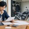 ローン契約書とバイクの鍵を前に売却手順を確認する日本人オーナー