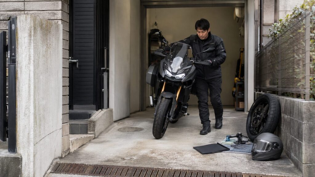 自宅の駐輪環境でツーリングバイクを押し引きする日本人ライダー 